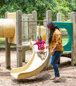 Terri watching her daughter play on the slide in the park. 